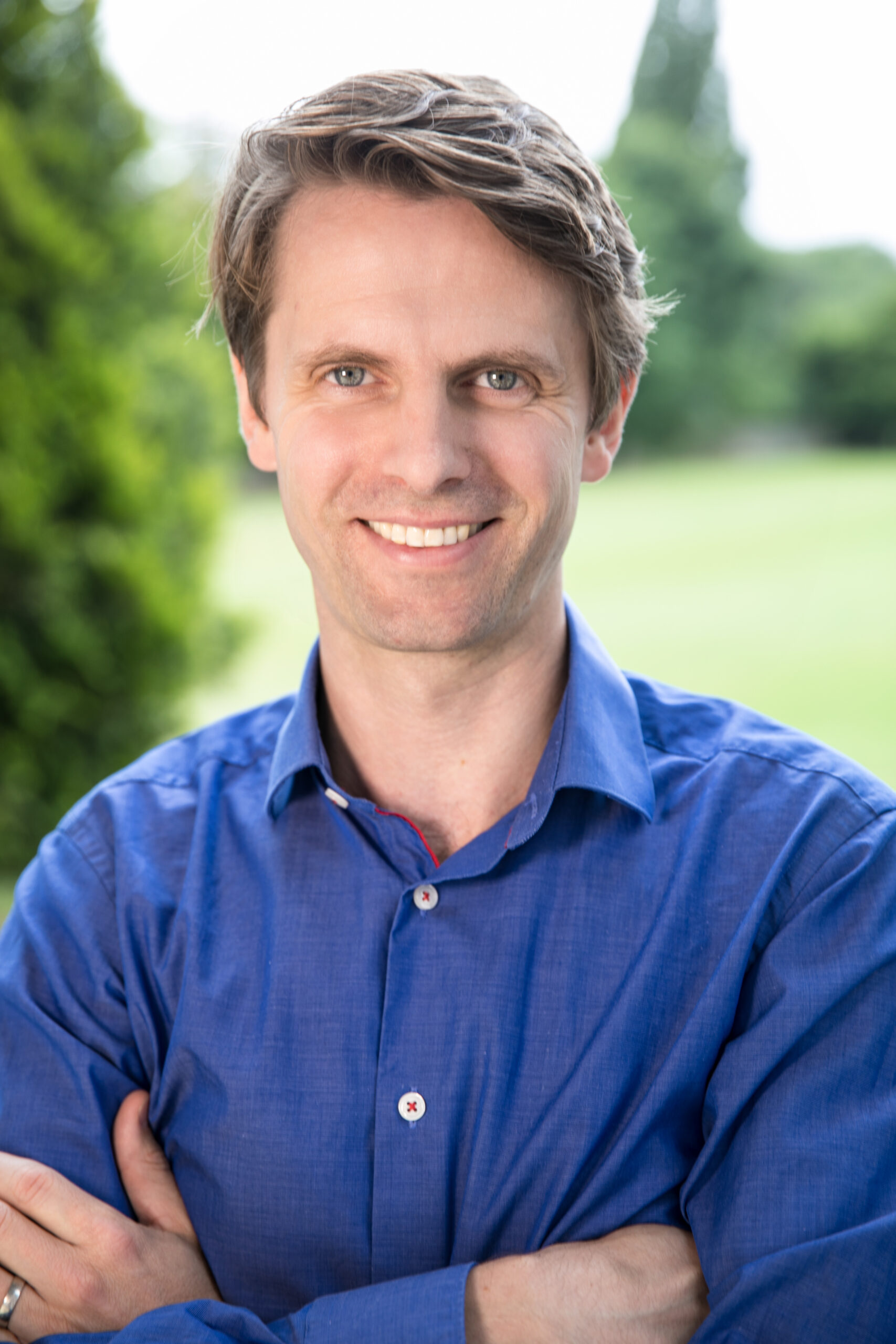 Corporate headshot of a brown haired man in a blue shirt