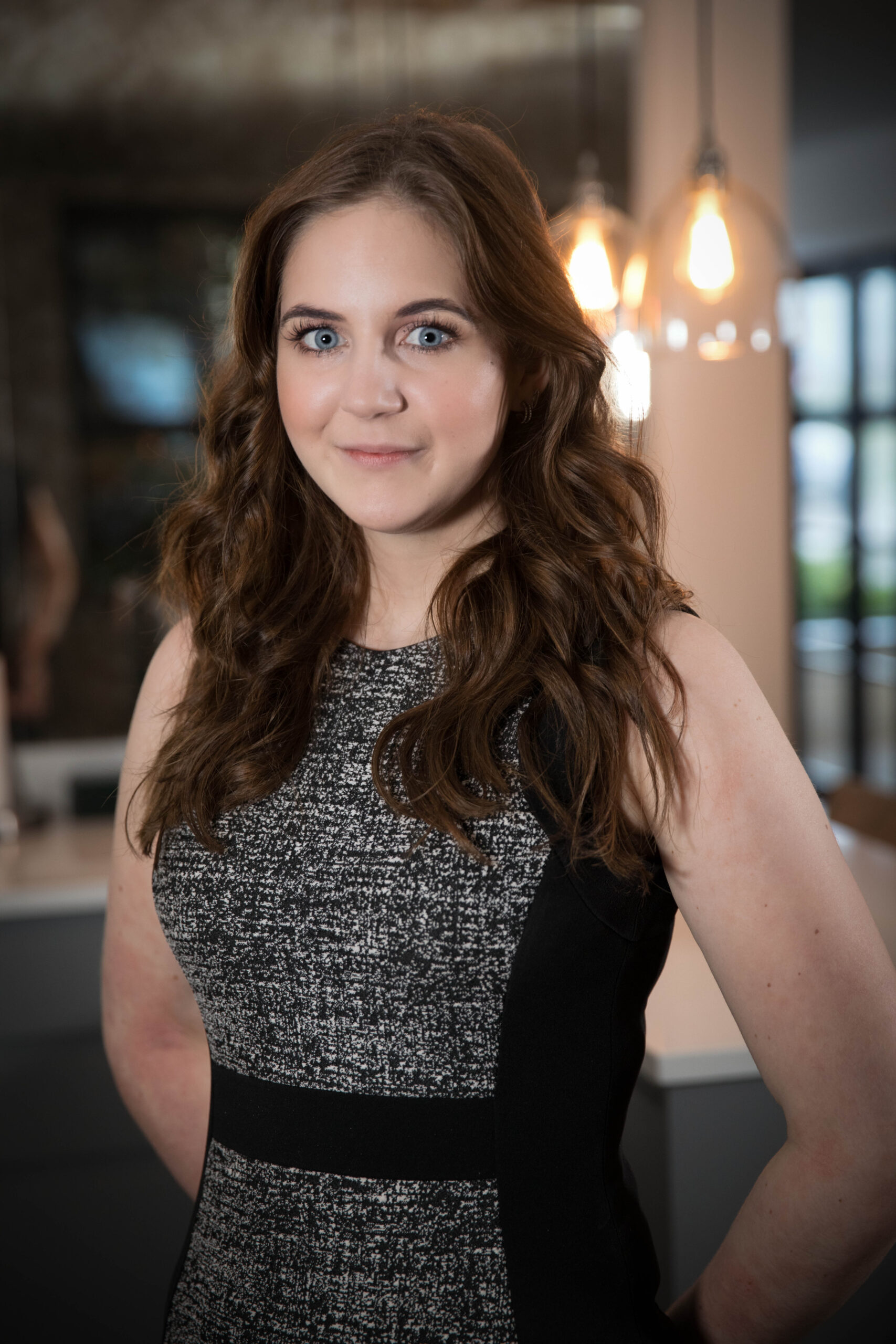 Corporate headshot of a brown haired women in a business pose wearing a dress